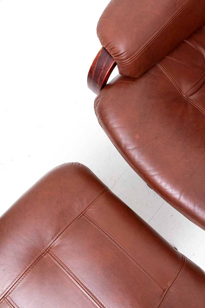 Draaifauteuil van bruin imitatieleer met verstelbare zitting en bijpassende voetenbankje