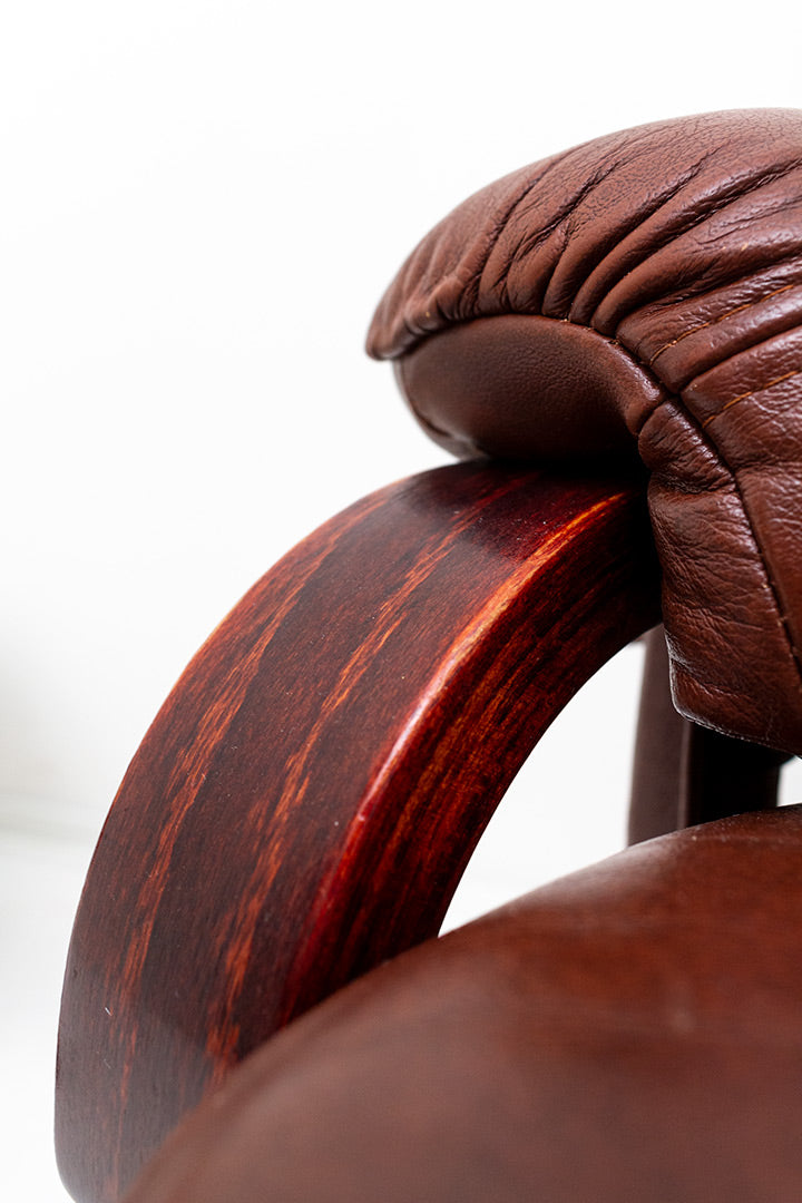 Draaifauteuil van bruin imitatieleer met verstelbare zitting en bijpassende voetenbankje