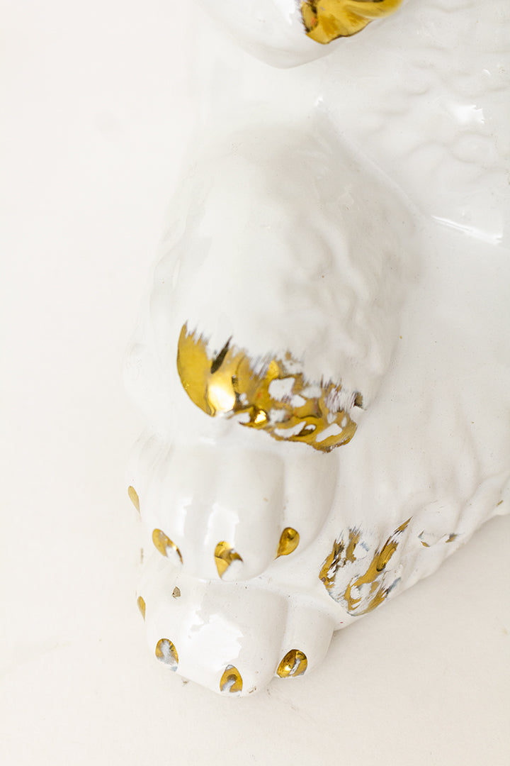 Groot beeld van een liggende witte poedel met vergulde details
