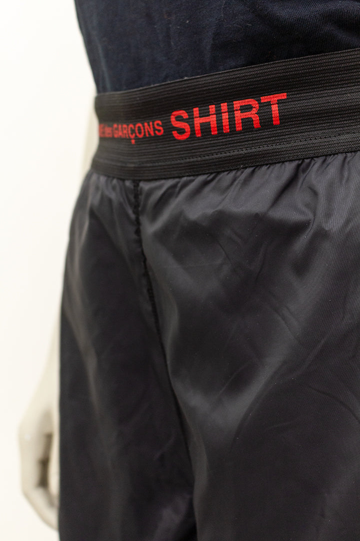Zwarte heren shorts/driekwart broek met rode biezen uit de SHIRT lijn Comme des Garçons